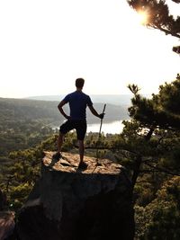 Rear view of man standing on mountain against clear sky