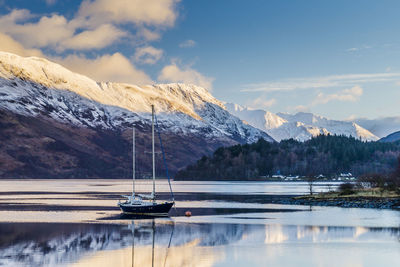 Scenic view of lake by snowcapped mountains against sky