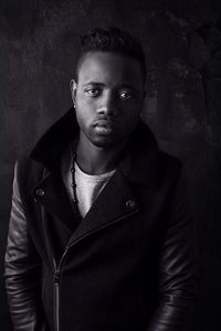 Portrait of young man standing against black background