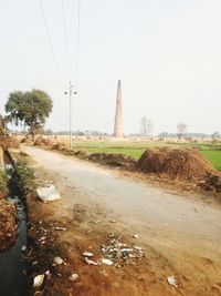 Road amidst field against clear sky