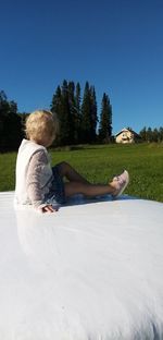 Woman sitting on field against clear sky