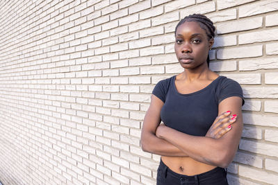 Portrait of young woman standing against wall