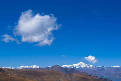 Scenic view of snowcapped mountains against blue sky