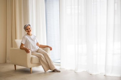 Side view of woman sitting on sofa at home