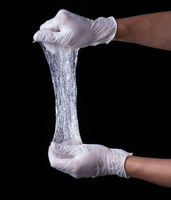Cropped hand of woman holding hands against black background
