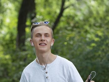 Young man with headphones standing in forest
