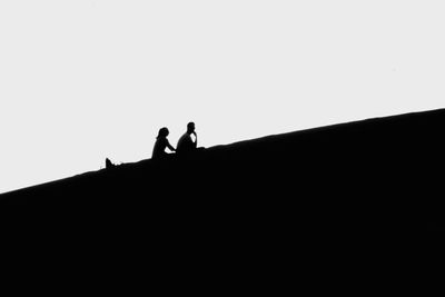 Low angle view of silhouette people standing on land against clear sky