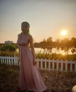 Portrait of woman in gown standing against sky during sunset