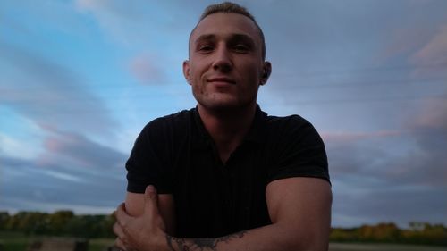 Portrait of young man looking away against sky