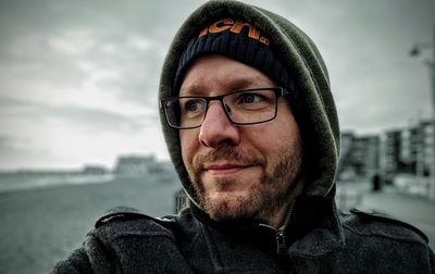 Portrait of man wearing eyeglasses against sky during winter