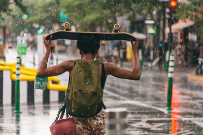 Rear view of man standing on wet street in rain