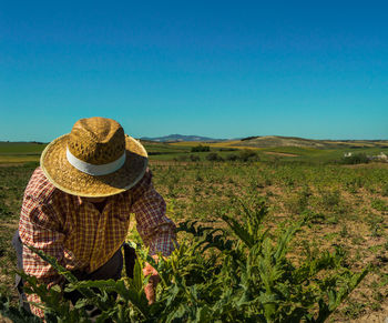 Man wearing straw hat working on field