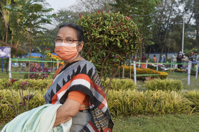 Portrait of an aged bengali woman wearing face mask during her visit at rabindra sarobar flower show