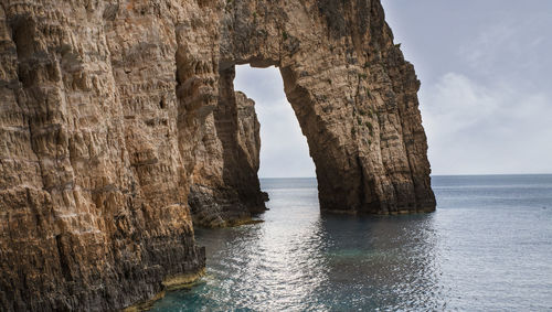 Rock formation in sea against sky