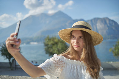 Portrait of young woman using smart phone against mountains