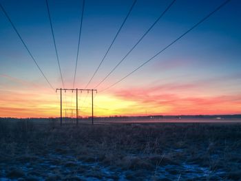 Electricity pylon on field against sky during sunset