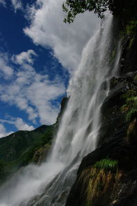 Scenic view of waterfall in forest against sky