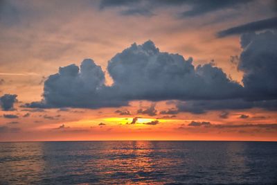 Scenic view of sea against dramatic sky during sunset