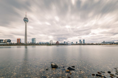 City at waterfront against cloudy sky