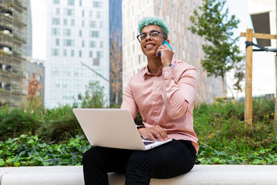 Young man using mobile phone sitting in city