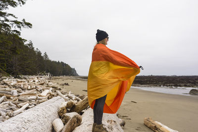 Side view of female hiker with blanket looking at view while standing on wood