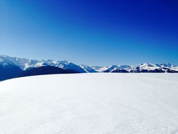 Scenic view of snow covered mountains against clear blue sky