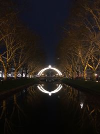 Illuminated bridge over river in city at night