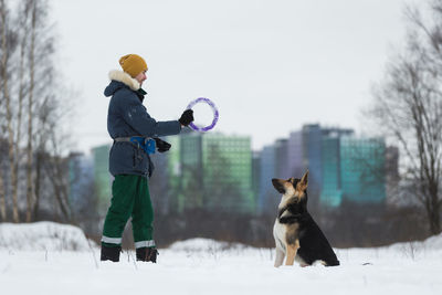 Man playing with dog during winter