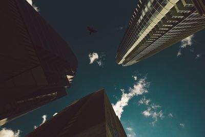 Low angle view of skyscrapers against cloudy sky