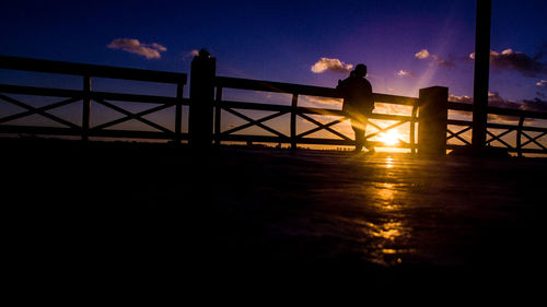 Silhouette people standing on bridge against sky during sunset