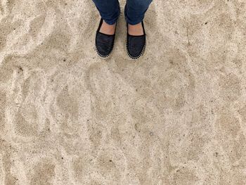 Low section of woman standing on sand at beach