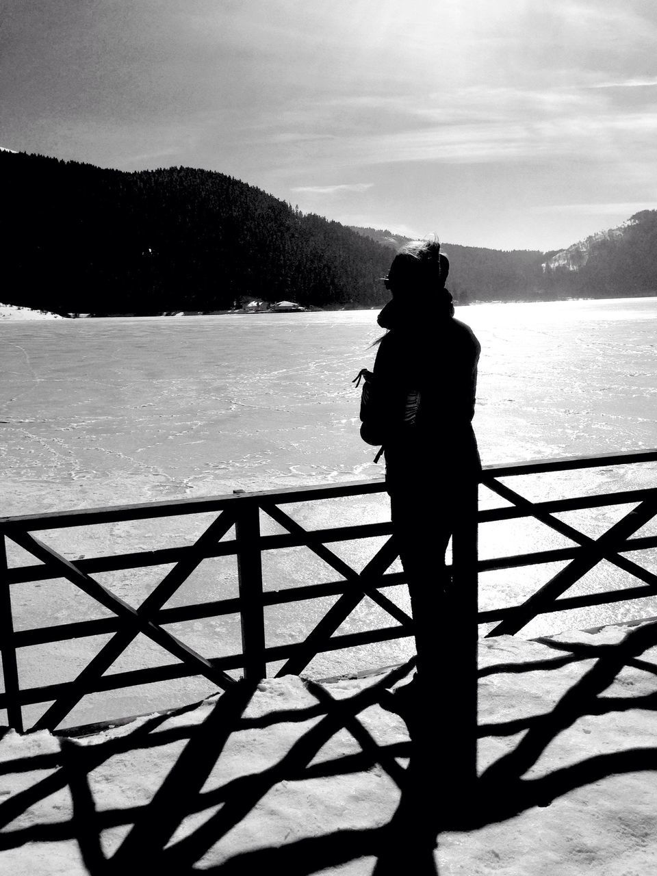 water, lifestyles, sky, rear view, silhouette, leisure activity, mountain, standing, men, sea, full length, railing, tranquil scene, tranquility, looking at view, nature, lake, beauty in nature