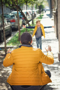 Happy boy running towards father on sidewalk in city