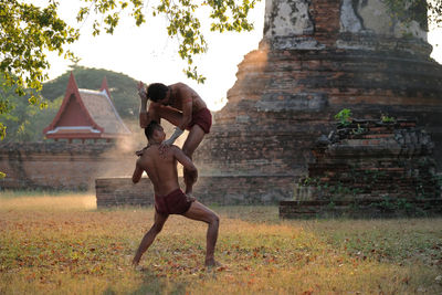 Shirtless men fighting on land