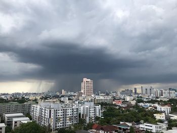 High angle view of buildings in city against storm clouds