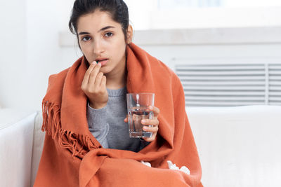 Portrait of ill woman taking medicine