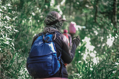 Rear view of woman standing amidst trees in forest