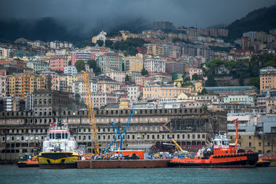 Boats in river by buildings in city