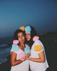 Portrait of friends standing at beach against sky