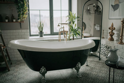 Luxury interior of big bathroom at modern african style with oval bathtub in natural lighting