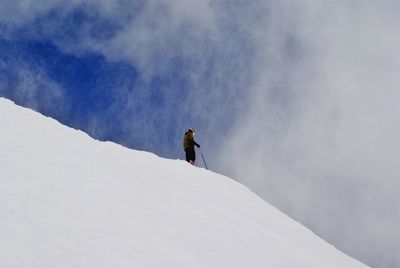 Person standing on snow covered slope against sky