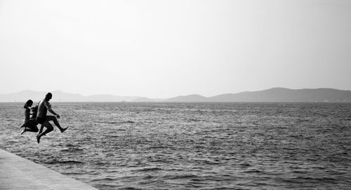 People on sea against clear sky