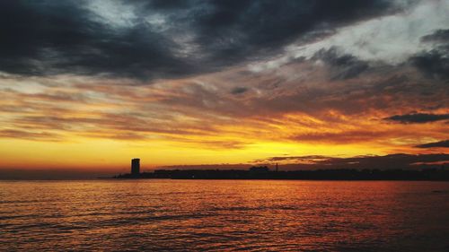 Scenic view of sea against dramatic sky during sunset