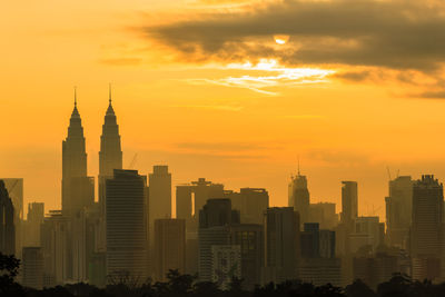 Modern buildings in city against sky during sunset