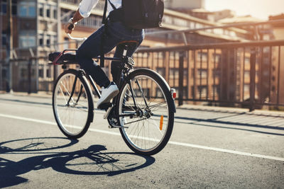 Low section of businessman riding bicycle on bridge in city