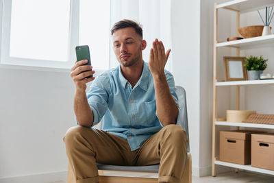 Young woman using mobile phone while sitting on sofa at home