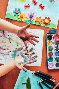 Little girl preschooler showing painted colourful hands. child having fun making a stamps