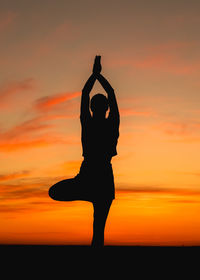 Silhouette person doing yoga against sky during sunset