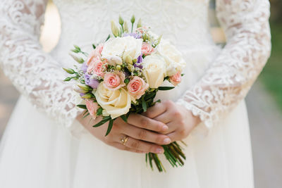 The hands of a young bride are holding a beautiful delicate wedding bouquet. 