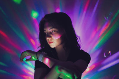 Young woman looking away against illuminated lights